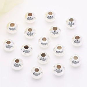 Polished silver spacing beads with textured holes for DIY jewelry making on white background