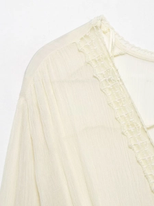Close-up of elegant lace neckline and textured crinkle fabric on cream blouse