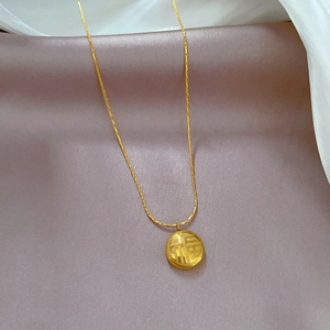 Gros plan d'un collier en acier titane doré avec pendentif Fu sur fond de soie