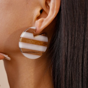 Close-up of geometric round earrings with striped wood and white resin texture