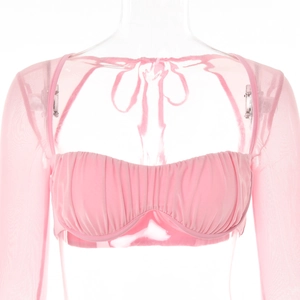 Détail d'un haut de bikini bandeau rose froncé avec manches longues en maille transparente
