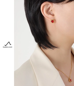 Detail showing gold plated heart necklace and earrings set with red zircon on a model