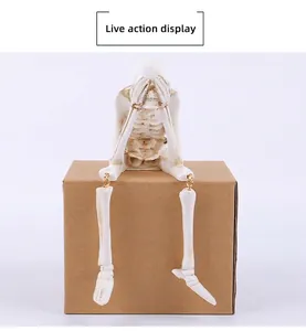 Detail of seated resin skeleton figurine with ivory finish and see no evil pose