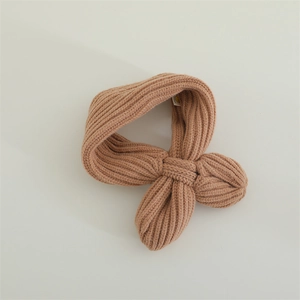 Detailed view of khaki knit scarf featuring a cozy bow knot and small yellow smiley face label