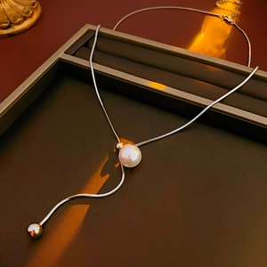 Detailed view of silver snake chain necklace featuring a white pearl and Y-shaped fringe
