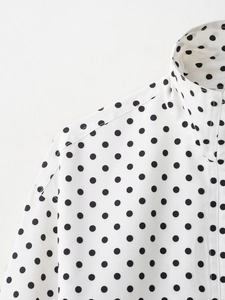 Vue détaillée de la blouse blanche à pois avec col montant et coutures sur les épaules