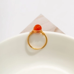 Close-up of handmade gold wire-wrapped ring with a luminous orange cat-eye stone