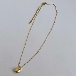 Detailed view of golden teardrop pendant necklace with lobster clasp and adjustable chain
