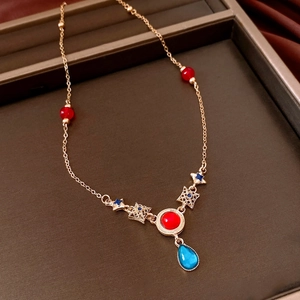 Detail view of vintage gold necklace with red blue resin pendants and stars on a tray