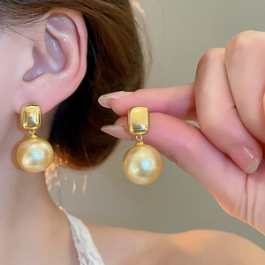 Gros plan d'un modèle portant des boucles d'oreilles en perles champagne plaquées or 18 carats