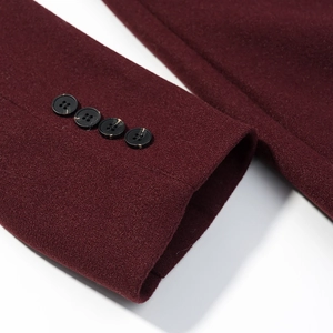 Detail of burgundy wool coat cuff featuring four decorative black marbled buttons