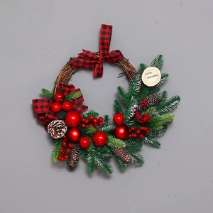 Christmas wreath with red balls, pine cones, and checkered bow on a natural rattan base