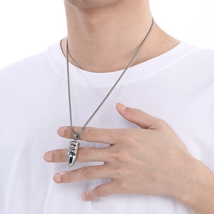 Close-up of men's silver bullet pendant necklace with textured chain on model