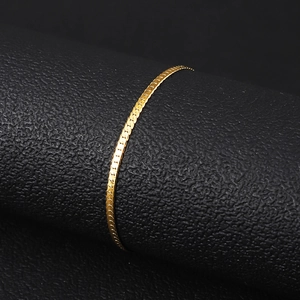 Detail view of a 18K gold-plated stainless steel flat snake chain bracelet on a black display