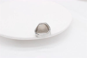 Detailed close-up of a silver-toned square gemstone ring on a minimalist white display