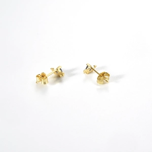 Macro shot of 925 silver gold stud earrings with dark gemstone inlays on white