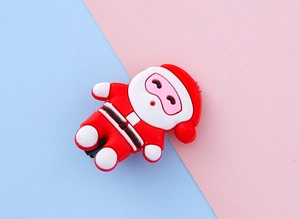 Détail d'une pince à cheveux Père Noël mignonne en PVC souple sur un fond rose et bleu
