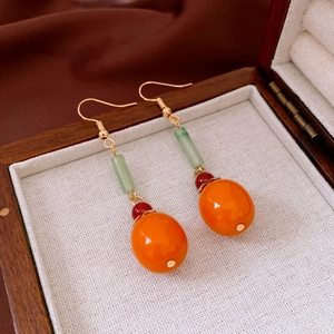 Detail of persimmon-style earrings with green and orange beads in a jewelry box