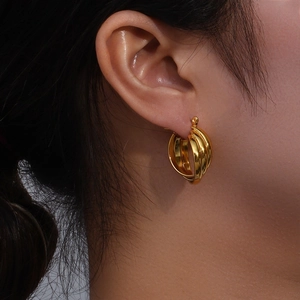 Women's gold triple-layered curved hoop earrings with textured metal finish on model