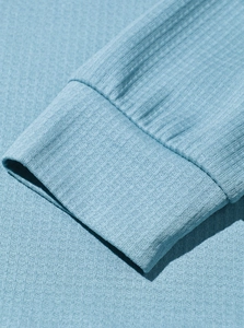 Macro shot of light blue waffle knit sleeve cuff showing textured fabric and stitching