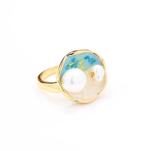 Détail d'une bague en émail bleu et or ornée de perles naturelles blanches de qualité