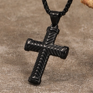 Close-up of black cross pendant with engraved chevron pattern and link chain