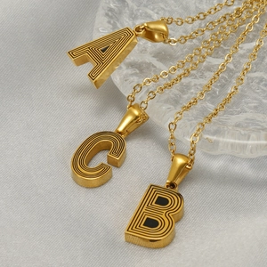 Three gold stainless steel layered necklaces featuring 3D letter A, B, and C pendants