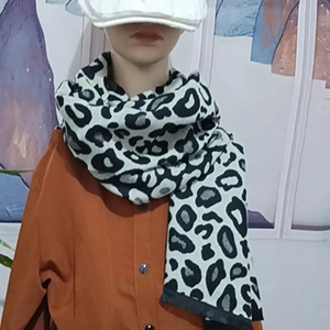Detailed close-up of thick knit leopard print scarf styled on a female model