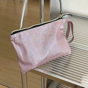 Detailaufnahme der rosa Glitzer-Kosmetiktasche mit Metall-Reißverschluss auf Silberregal