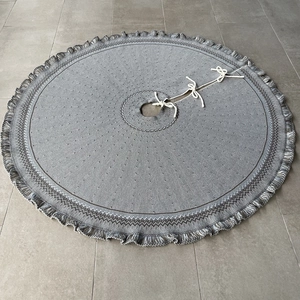 Detailed view of grey knitted Christmas tree skirt featuring tassels and tie closures