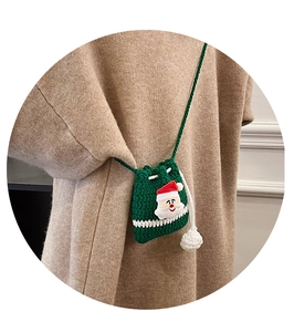 Detail of green Christmas drawstring bag with Santa Claus accent and white pom-poms