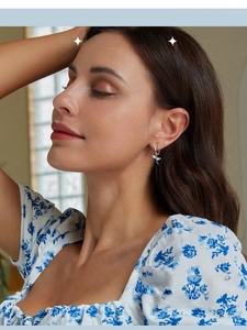 Close-up of a blue enamel hummingbird hoop earring worn on an ear with zircon accents