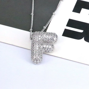 Macro shot of a letter F pendant necklace with pavé cubic zirconia on a silver chain