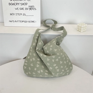 Détail d'un sac en toile fleurie vert haricot avec motifs blancs et large bandoulière