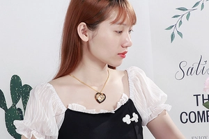 Close-up of a gold heart pendant necklace with tortoiseshell texture on a female model