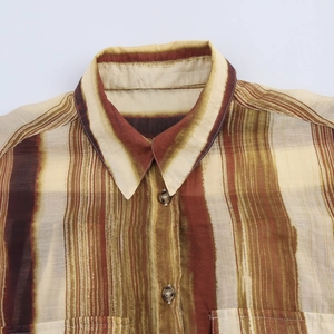 Gros plan détaillé du col d'une chemise rayée marron et texture du tissu avec boutons