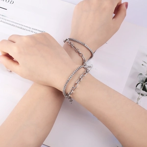 Minimalist double-layered silver heart magnet bracelets for couples on modern magazine background