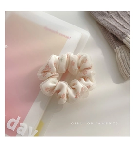 Dettaglio dell'elastico scrunchie in rete beige a fiori su tavolo bianco per donna