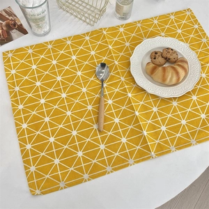 Detail of yellow geometric linen placemat with white triangular pattern in breakfast scene