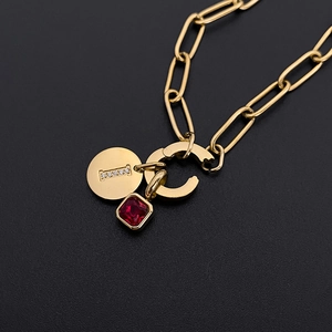 Dettaglio della collana a catena gold con ciondolo lettera I e pietra rossa