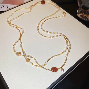 Detail of layered gold beaded necklace with rose pendants and sunstone gemstone beads