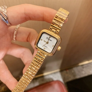 Macro shot of square gold women's watch with mother of pearl dial and diamond markers