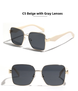 Detail view of large gold metal square sunglasses with beige temples and grey lenses