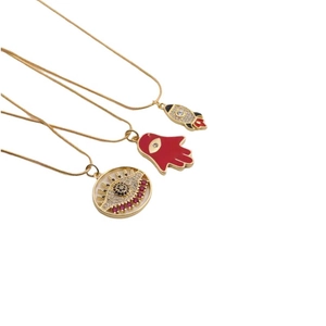 Detailed view of three gold plated necklaces featuring rocket, Hamsa hand, and evil eye charms