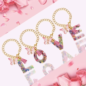 Set of four cute resin letter keychains spelling LOVE with pink butterfly charms and tassels