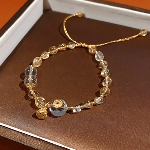 Detail of beaded citrine and quartz bracelet with a golden lotus pod charm on leather