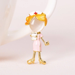 Macro shot of a nurse brooch with pink enamel uniform and opal face in gold plating