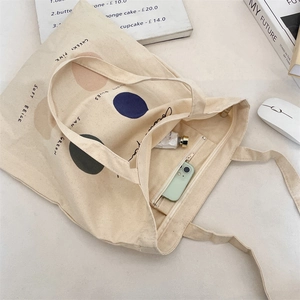 Detail of canvas tote bag showing interior zipper pocket holding a phone and cosmetics