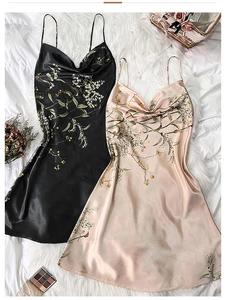 Flat lay of satin slip nightwear in black and pink on a white plush rug with accessories
