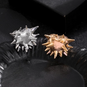 Macro detail of punk urchin rings in silver and gold plating on a textured black tray